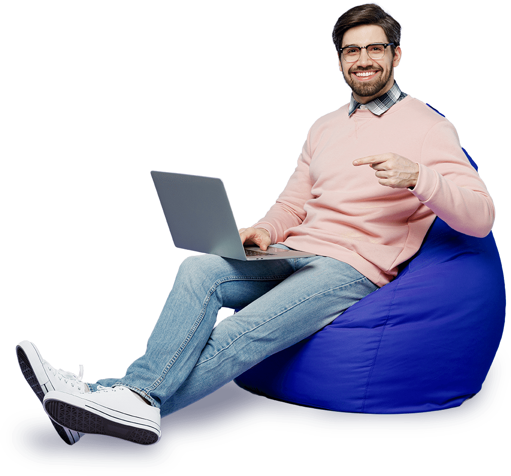 Man in pink sweater sitting on blue bean bag chair with laptop
